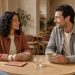 Un homme et une femme discutent avec le sourire lors d’un premier rendez-vous dans un café chaleureux.